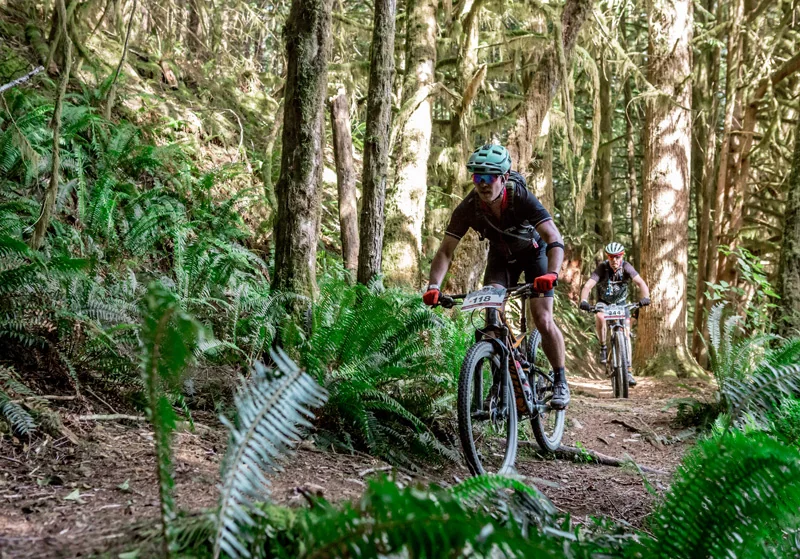 Brian racing a mountain bike through a forest